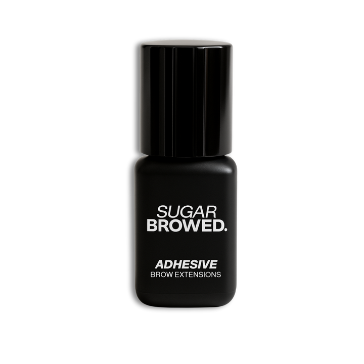 Black bottle of SUGAR BROWED. Adhesive for brow extensions on clean studio background – professional eyebrow glue for long-lasting results